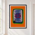 A framed art print featuring a stylized sardine can illustration with the words 'ANCHOVIES' and 'IN OLIVE OIL' on an orange background, hung on a white wall next to a window.