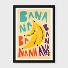 A framed retro-style art print featuring the word 'BANANA' repeated in bold pastel colors around a large yellow banana illustration, shown against a light gray background.
