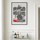 A framed black and white travel poster of Barcelona with a red cable car illustration, displayed on a white wall above a glass shelf with bottles.