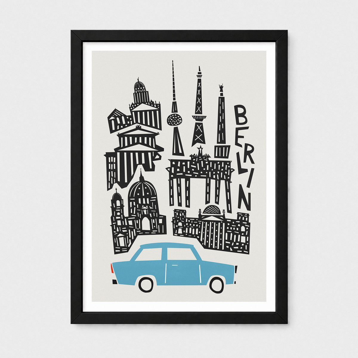 A framed Berlin cityscape art print featuring black architectural silhouettes and a light blue car on a light gray background, shown in a black frame with a white mat against a light gray wall.