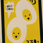 Cartoonish mayo typography label with a face on a yellow background, featuring the word 'Delicious'.