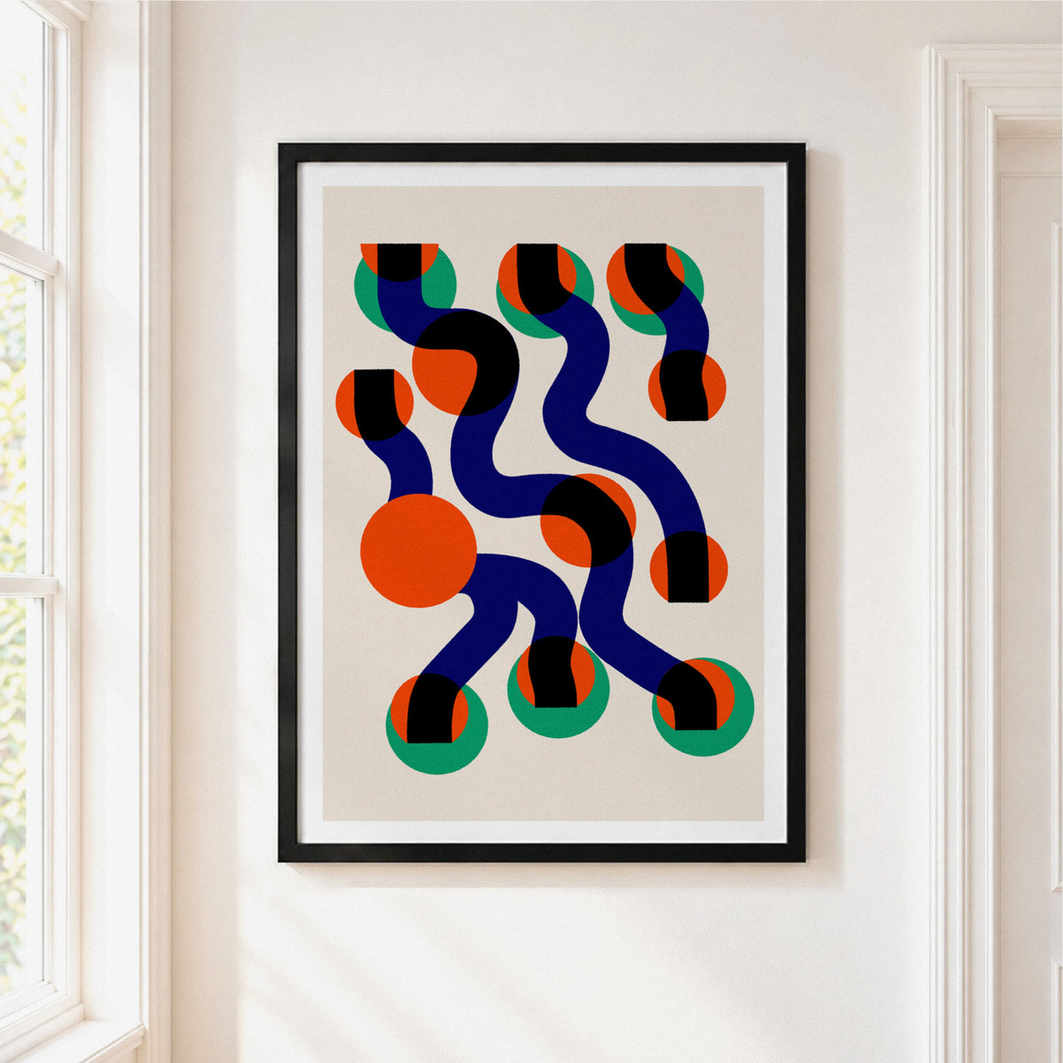 Framed abstract wall art hanging on a white wall beside a window. The print features flowing dark blue lines, orange circles, black and green striped accents, and a light beige background, enclosed in a black frame with a white mat.