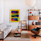 Modern living room with a colorful abstract painting on the wall, a white sofa, wooden coffee table, and a bookshelf.