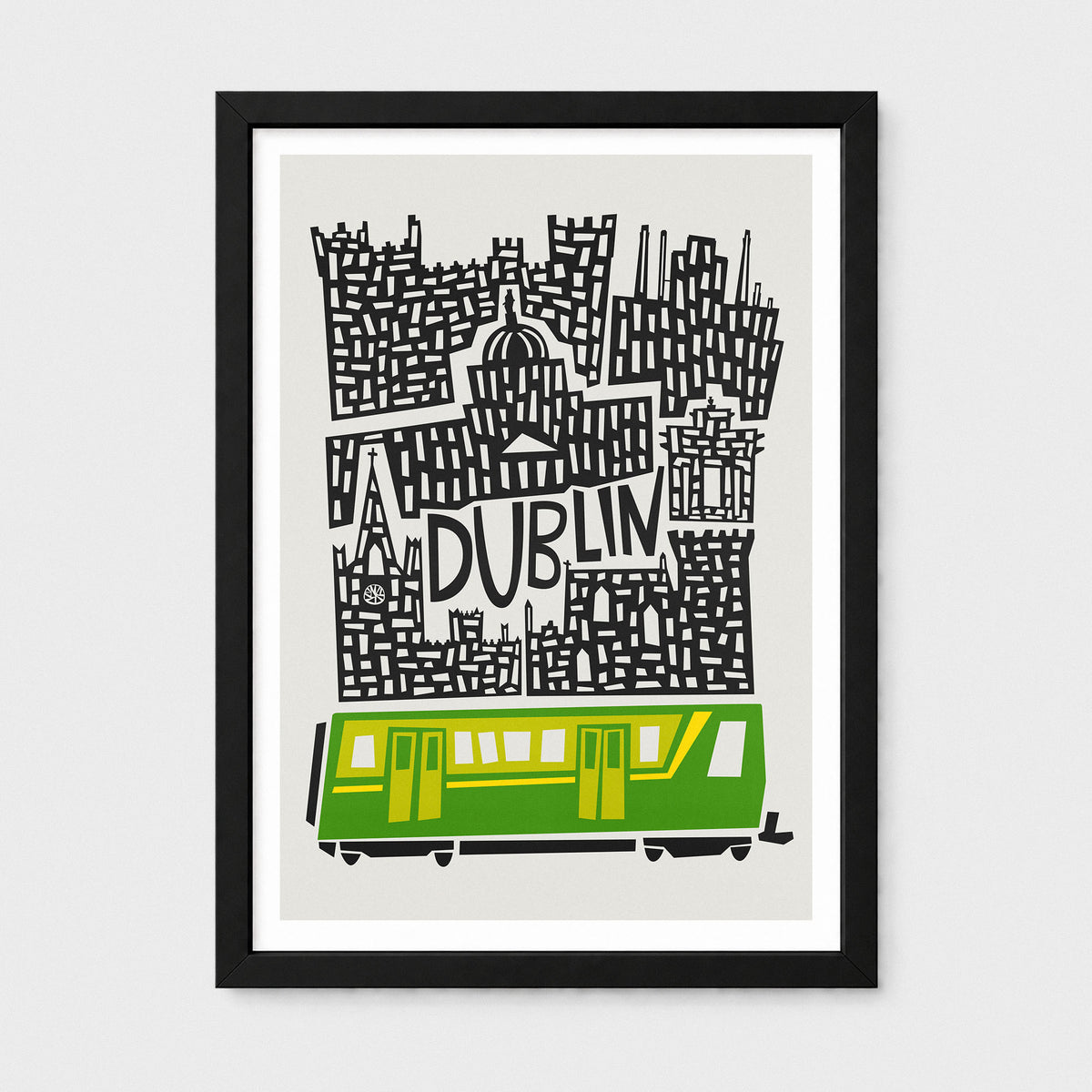 A framed art print featuring a stylized black and white cityscape with the word 'DUBLIN' and a green and yellow train at the bottom, shown against a light gray background.