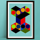 Framed abstract geometric wall art print featuring bold 3D cube shapes and circles in red, yellow, green, blue, purple, black, and orange on a light blue background, shown against a teal wall.