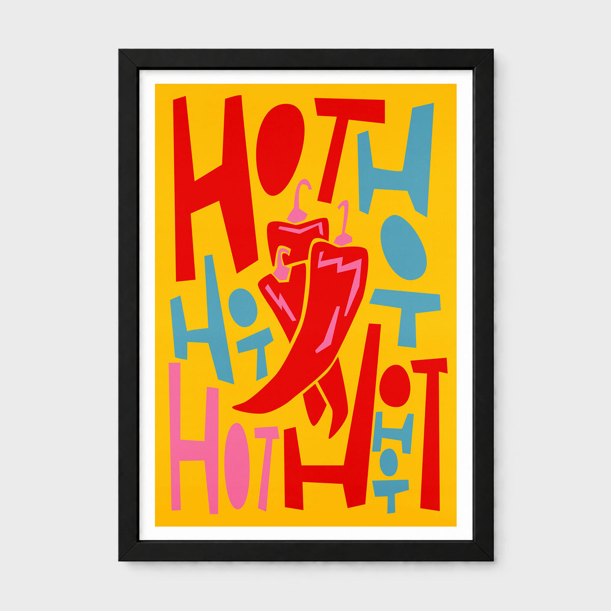 A framed art print featuring a bold retro illustration of some chilli's with the word 'HOT' repeated in red, pink, and blue on a bright yellow background, with a large red chili pepper illustration in the center. The print is housed in a simple black frame with a white mat, set against a neutral light gray background.