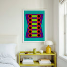 A framed abstract art print featuring colorful geometric circles on a teal background, hanging on a white wall above a yellow shelf in a bright bedroom setting.