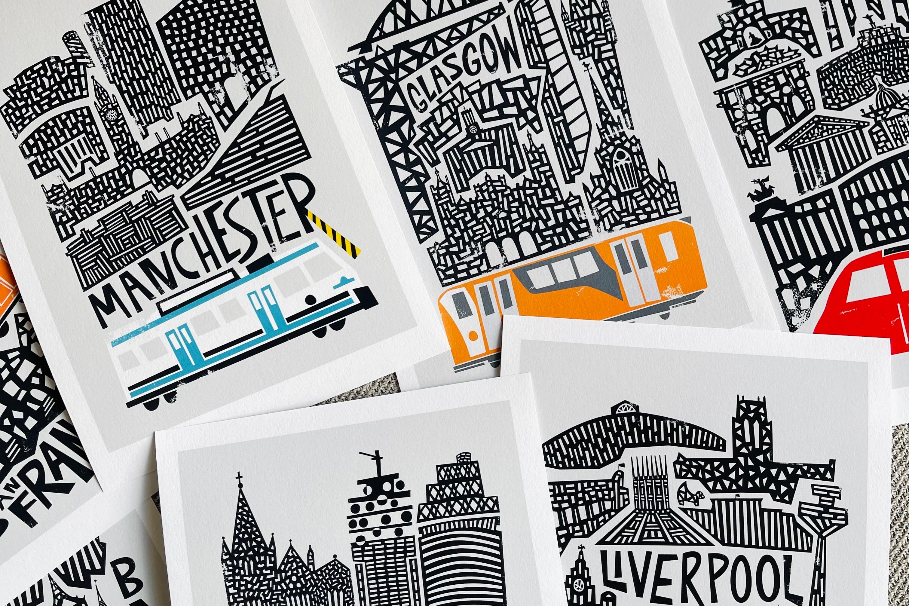 Collection of Fox and Velvet prints with black and white illustrations of cityscapes and text, featuring cities like Glasgow, Manchester, and Liverpool.