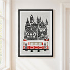 A framed art print featuring a stylized black and red Istanbul skyline with a tram and the word 'ISTANBUL', displayed on a light beige wall next to a window.