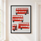 London red bus illustration in a black frame on a cream white wall near a window.