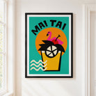 A framed 'Mai Tai' cocktail art print with a black frame and white mat, hanging on a white wall next to a window.