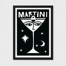A framed black and white art print featuring a stylized martini glass with eyes, the word 'MARTINI' at the top, and small celestial shapes on a light gray background.
