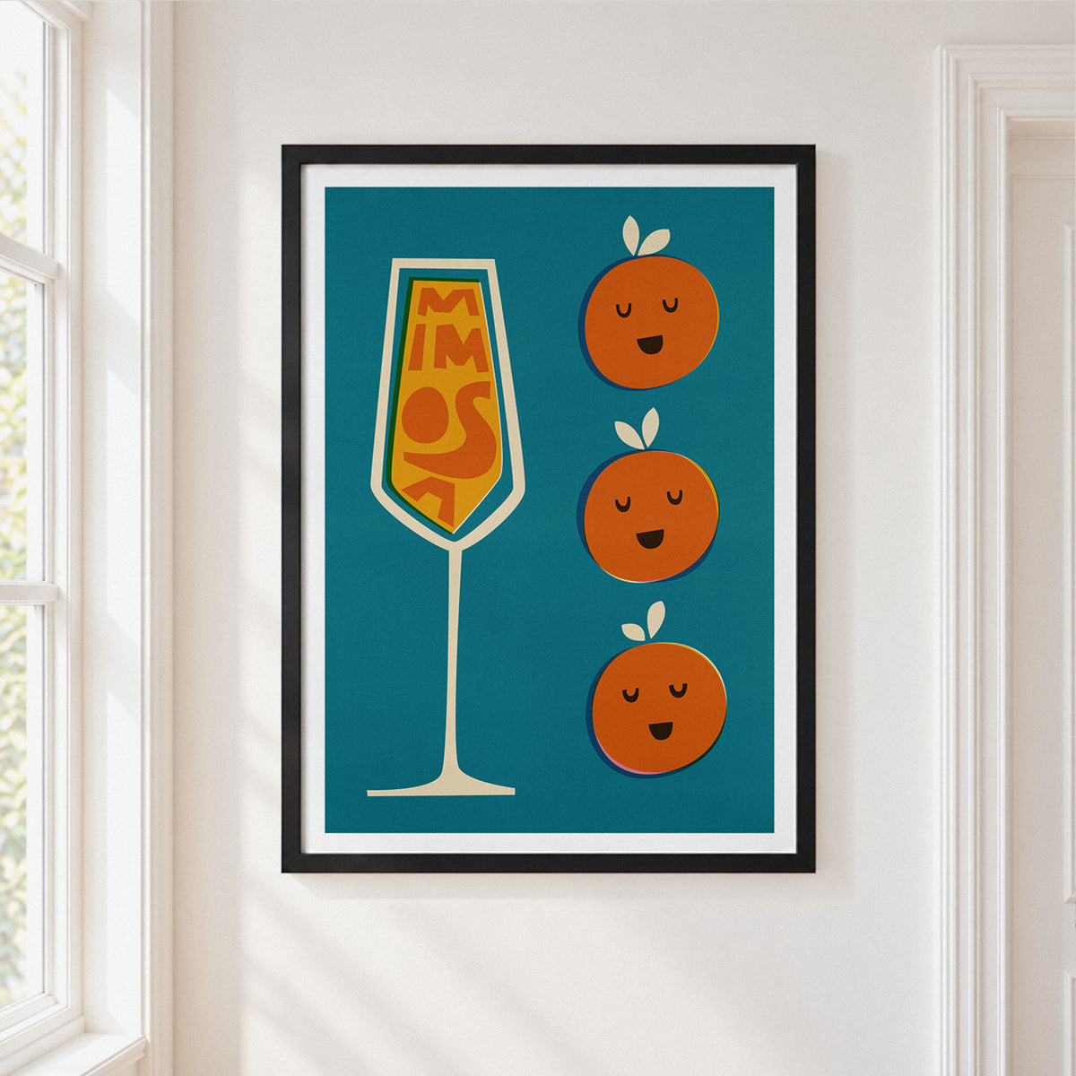 A framed art print hanging on a white wall next to a window. The print features a teal background with a stylized champagne flute filled with orange slices spelling 'MIMOSA' and three cute orange characters with smiling faces.