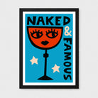 A framed art print featuring a retro-style illustration of a red cocktail glass with a female face, the text 'NAKED & FAMOUS' in black, and two cream stars on a bright blue background, shown in a black frame against a light gray wall.