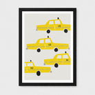Framed wall art featuring four stylized yellow taxis on a light gray background, shown in a black frame with a white mat against a light gray wall.