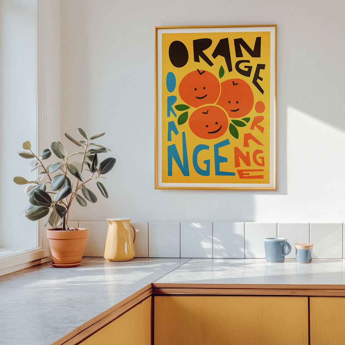 A framed retro-style orange poster hangs on a white kitchen wall above a countertop, with a potted plant, yellow pitcher, and blue mugs nearby.