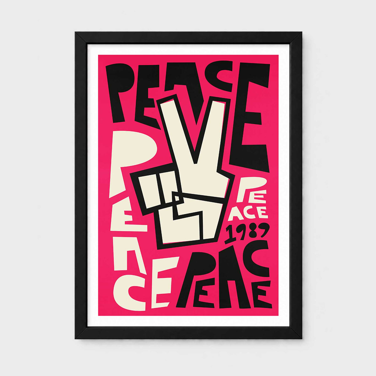 A framed art print featuring a bold retro graphic with the typography lettering 'PEACE' repeated in black and cream lettering over a bright pink background, with '1989' in white. The print is enclosed in a white mat and a slim black frame, shown against a light gray wall.