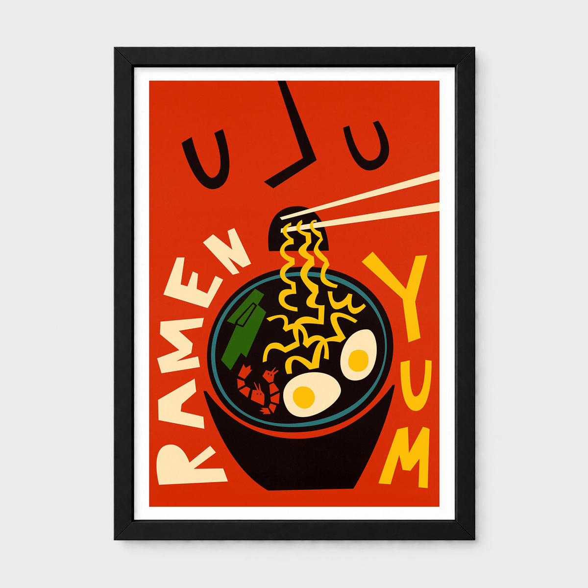 A framed retro-style ramen poster with bold graphic illustration, featuring a bowl of ramen noodles, chopsticks, egg halves, and vertical text reading 'RAMEN' and 'YUM' on a red background, shown against a light gray wall.