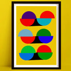 A framed abstract geometric art print featuring colorful semi-circles and arcs on a bright yellow background, leaning against a matching yellow wall.