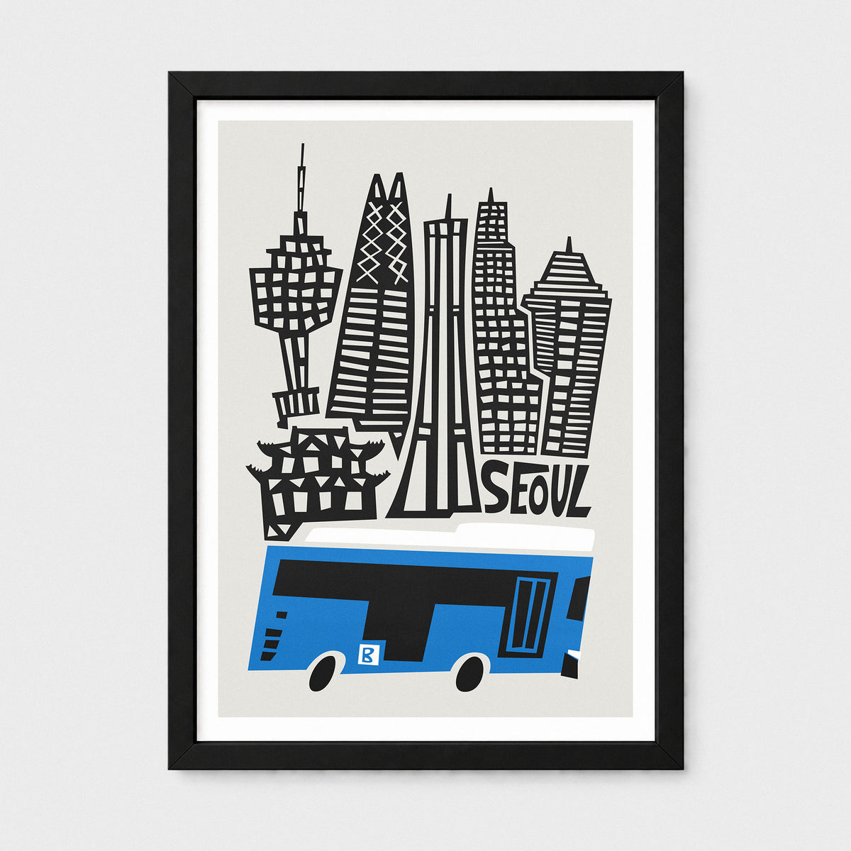 A framed art print featuring a stylized illustration of Seoul, South Korea, with black skyscrapers and a blue bus on a light gray background, enclosed in a black frame with a white mat.