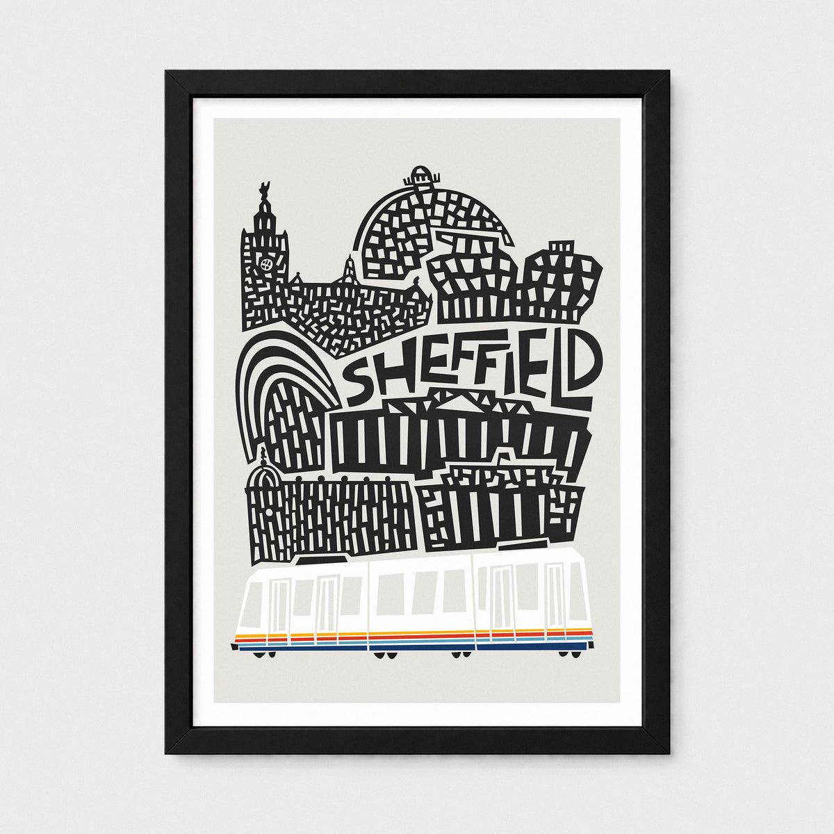 A framed art print featuring a stylized black and white illustration of Sheffield landmarks with the word 'SHEFFIELD' in bold letters, plus a white tram with orange and blue stripes at the bottom, shown on a light gray background.