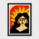 A framed art print featuring a stylized graphic portrait of a woman with a sun motif in the background, presented in a black frame against a light gray wall.