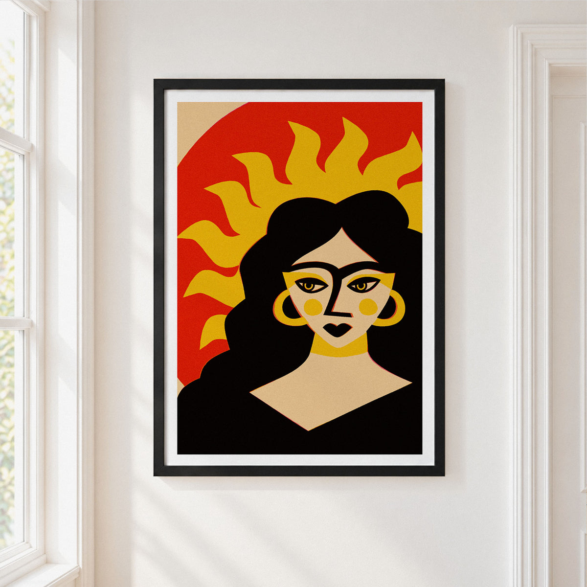 A framed art print featuring a stylized woman with a sun motif, hung on a white wall next to a window.