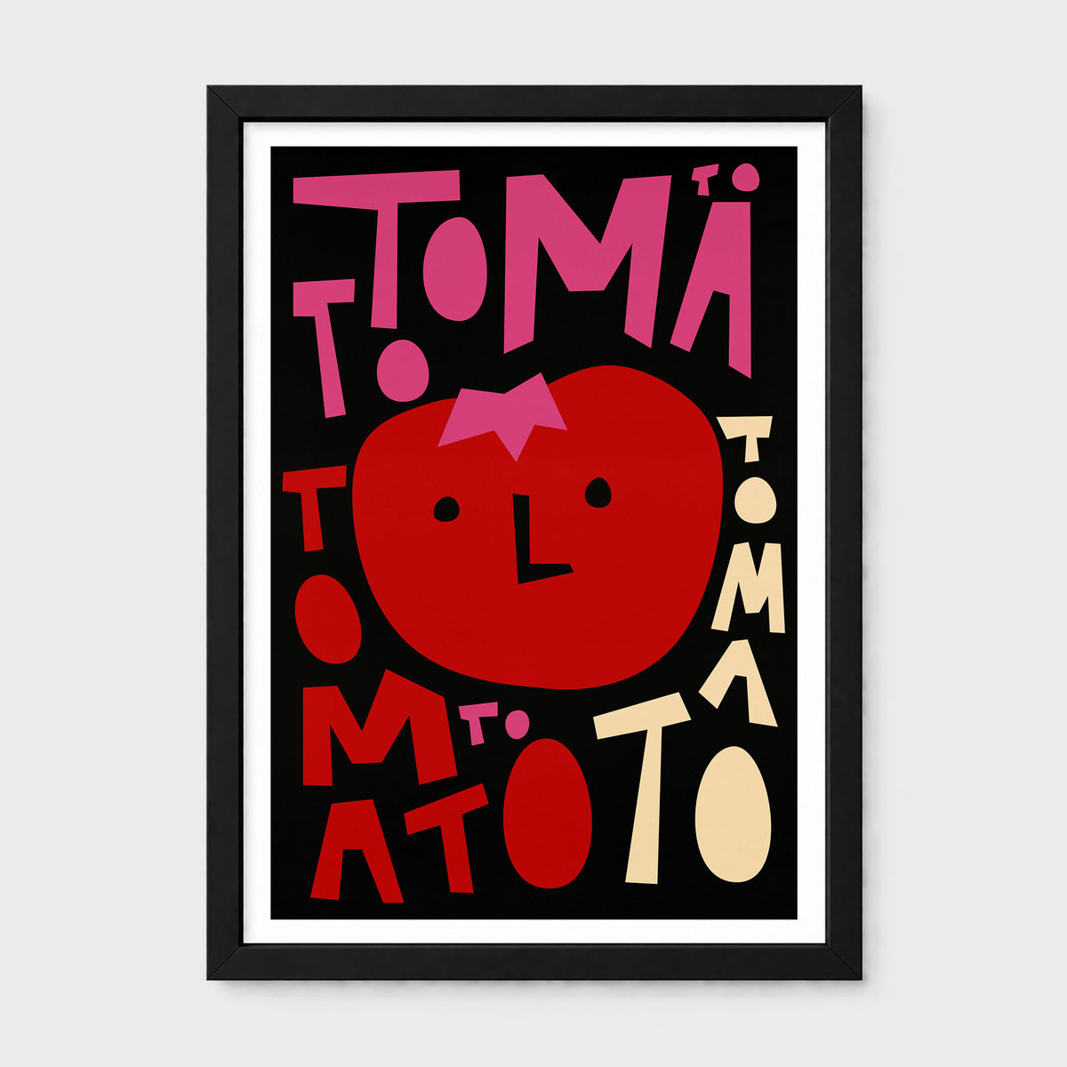 A framed typographic art print featuring a stylized red tomato face surrounded by the word 'TOMATO' in bold pink, red, and cream lettering on a black background, shown against a light gray wall.