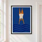 Framed wall art featuring a stylized wild swimming figure diving headfirst into blue waves, hung on a white wall next to a window.