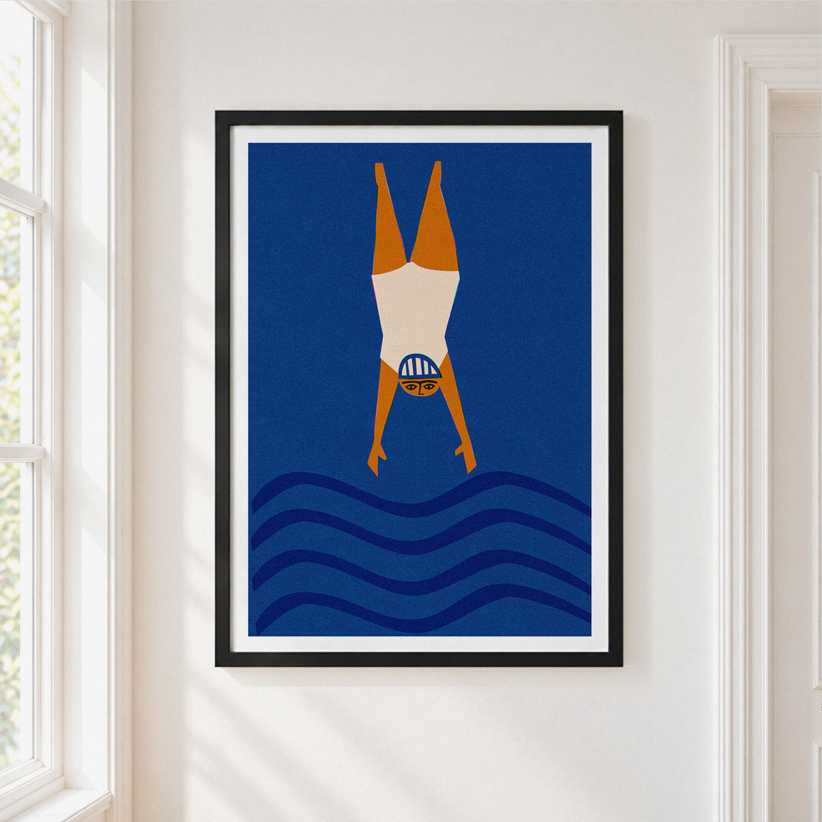 Framed wall art featuring a stylized wild swimming figure diving headfirst into blue waves, hung on a white wall next to a window.