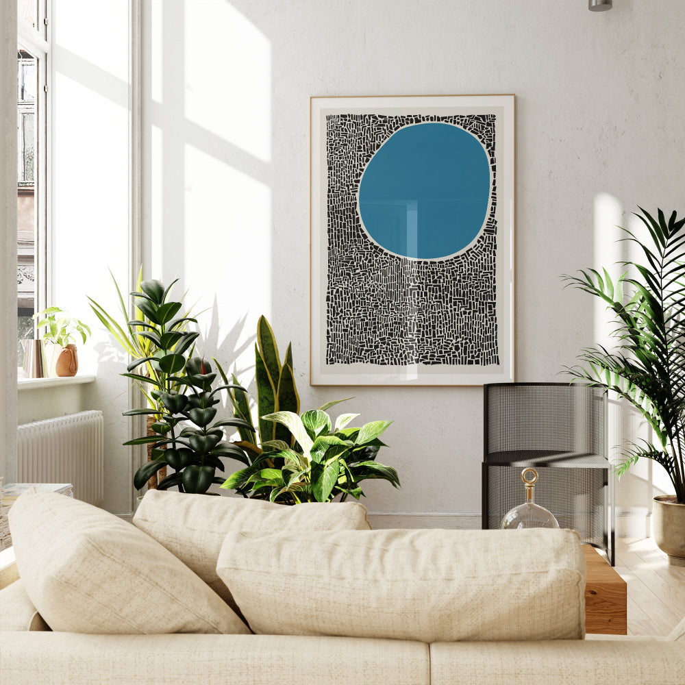 A large framed abstract blue and black print displayed in a modern white living room filled with plants, lending boldness and calm to the contemporary decor.