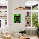 Aries poster framed above a cream-coloured sofa in a light-filled room with indoor plants and woven lighting.