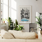 Framed Berlin cityscape artwork displayed above a neutral-toned sofa in a plant-filled living room, creating a modern, travel-inspired vibe.
