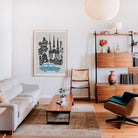 Berlin poster with a retro blue car grounding the scene, hanging in a mid-century modern interior with warm wood furniture and curated decor.
