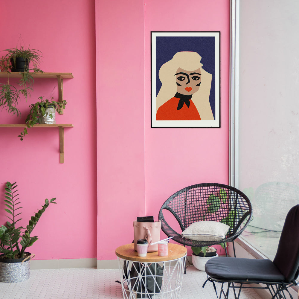 Blonde portrait print hanging on pink wall above indoor plants and black café chairs