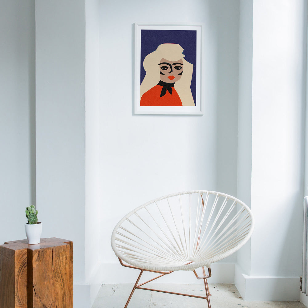 Blonde graphic portrait framed in a white minimalist room with natural wood and wire-frame chair