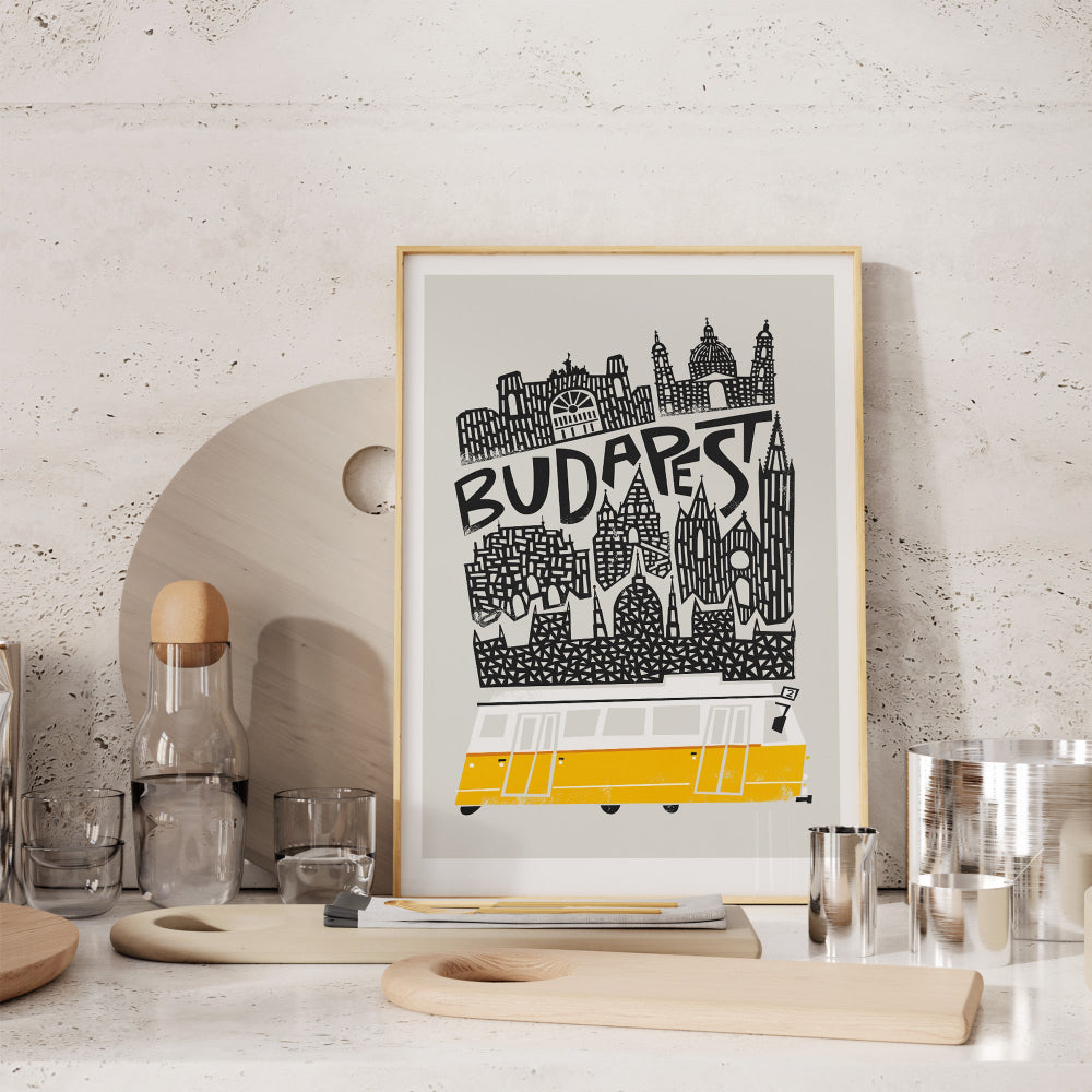 The Budapest skyline poster propped against a white wall in a modern kitchen space, styled with clean surfaces and glassware.