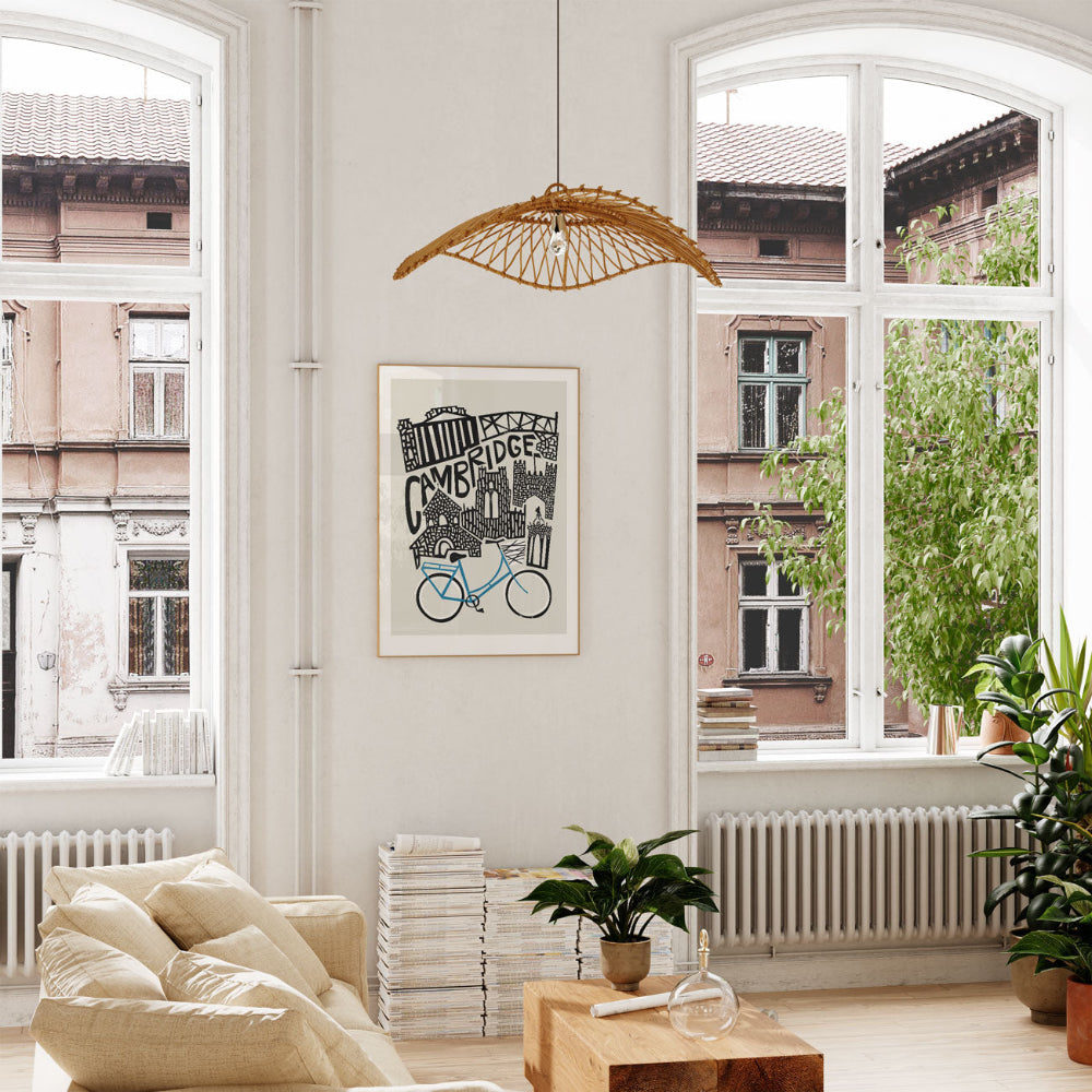 Framed Cambridge skyline print hanging in a sunlit room with arched windows and leafy plants, adding a touch of academic charm to the interior.