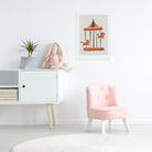 Framed carousel horse artwork in a child’s room, styled with pale furniture and pink chair