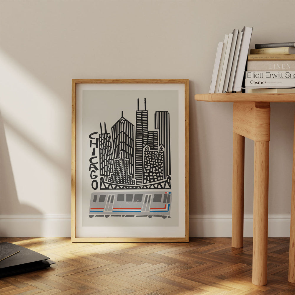 Framed Chicago skyline print leaning against a wall in a warm-toned interior with wooden flooring, adding urban charm to a cosy, creative space.