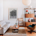 Framed Chicago cityscape print with CTA train on a pale wall in a stylish mid-century modern living room, complete with bookshelves and a minimalist aesthetic.
