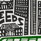A close-up of a graphic print featuring black stylized buildings, large letters, and a green horizontal band at the bottom on a white background.