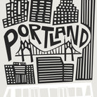 Black and white graphic art print featuring a stylized city skyline with the word 'PORTLAND' in large bold letters, a suspension bridge, and multiple buildings.