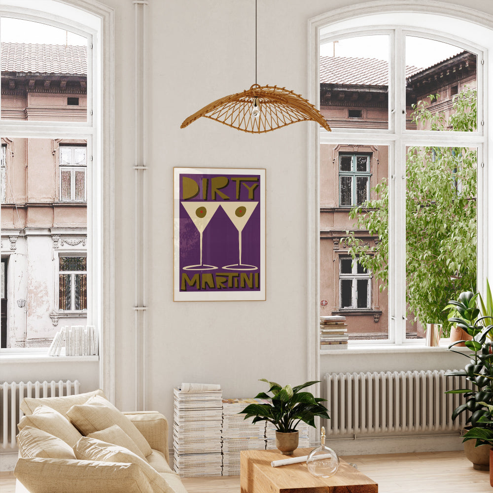 Dirty Martini poster framed above a bright window nook with light wood floors and leafy indoor plants.