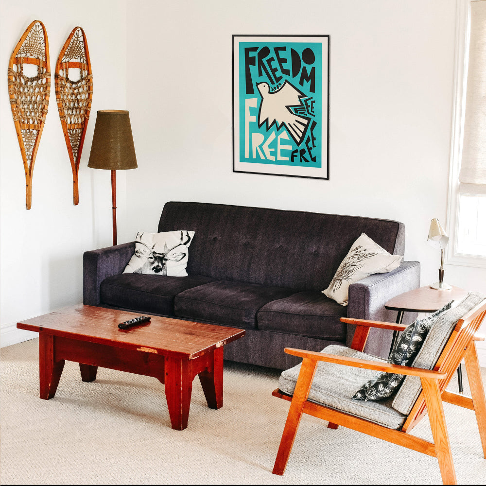 Freedom artwork hanging above black sofa in a retro-inspired living room with wood and ski decor
