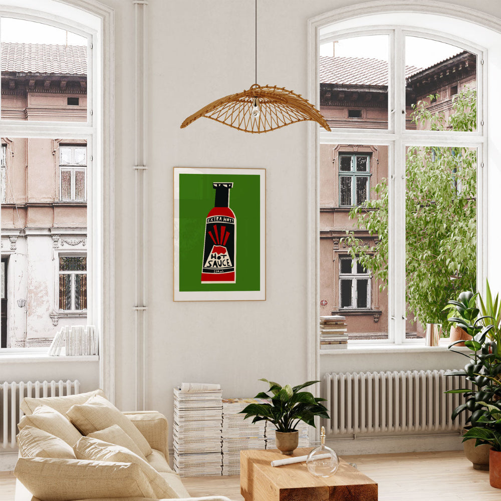 Extra Hot Sauce print framed above a cream sofa in a bright space with tall windows and indoor plants.