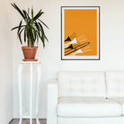Trombone and trumpet art print hanging above a white sofa and tall plant in a minimalist room