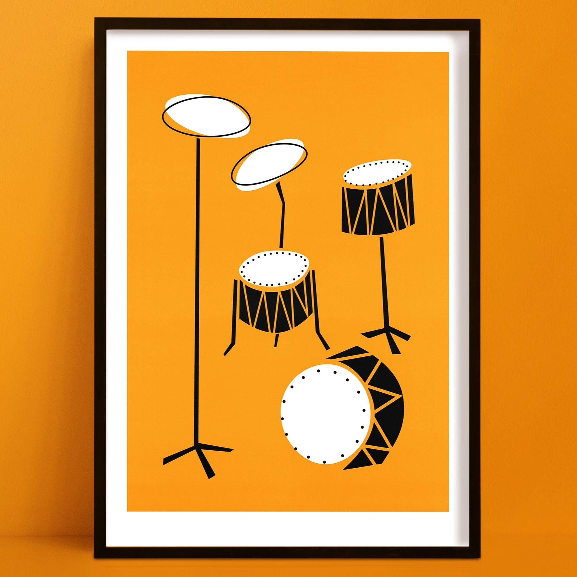 Framed abstract drum kit print with bright orange background and stylised black-and-white drums, displayed on an orange wall