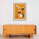 Framed drum kit print centred above a light wooden sideboard in a minimalist interior