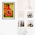 Framed Tomato Ketchup print placed on a crisp white wall beside open kitchen shelves, its mustard yellow background making the red bottle pop with bold contrast.
